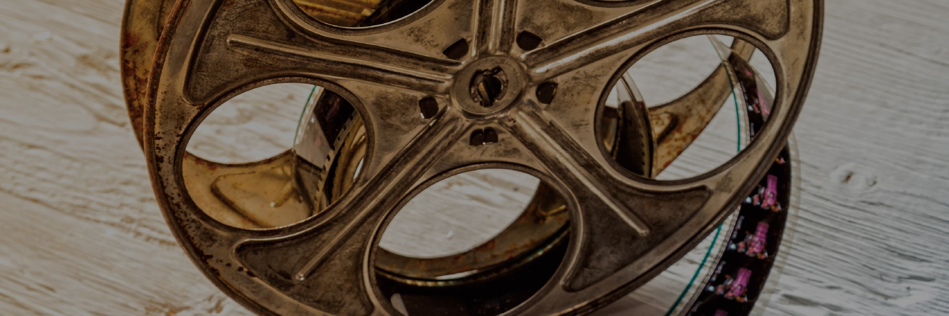 Film reel on wooden surface with visible film strip rolled inside the reel.