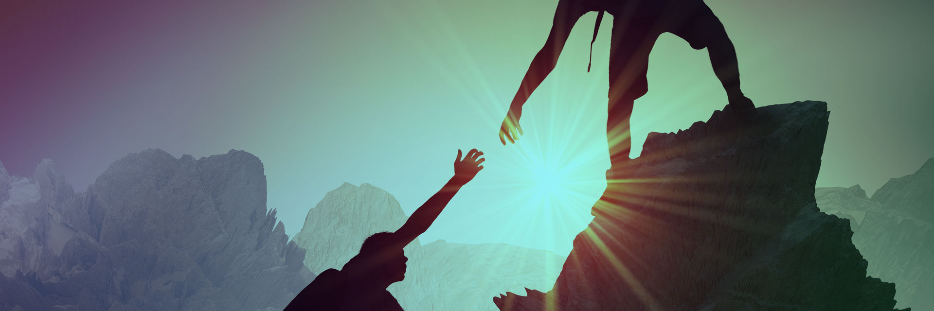 Two climbers reaching for each other on a rocky mountain silhouette with bright sunlight in the back